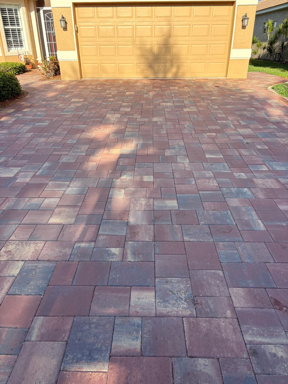 Paver driveway with textured red and gray bricks leading to a tan garage door.
